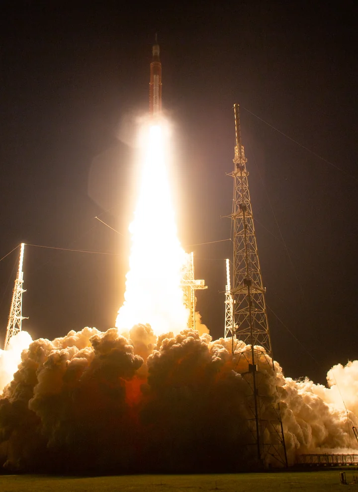 Ночной запуск миссии NASA Artemis I с космодрома Кеннеди и освещённый факел двигателей.
